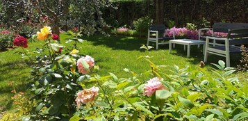 Un giardino con prato, panchine e piante fiorite.