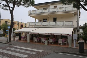 Un edificio a due piani con un caffè, un ristorante e una pizzeria al piano terra.