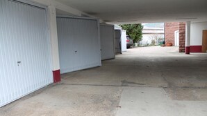 Een overdekte parkeerplaats met gesloten garagedeuren, een betonnen vloer en een bakstenen muur.