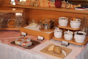 Un buffet proposant une variété de plats et de récipients, notamment un plateau de pâtisseries et plusieurs bols et bocaux contenant différents aliments.
