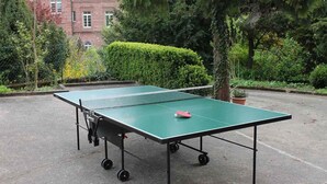Een tafeltennistafel buiten, met een net, wielen en een bat.