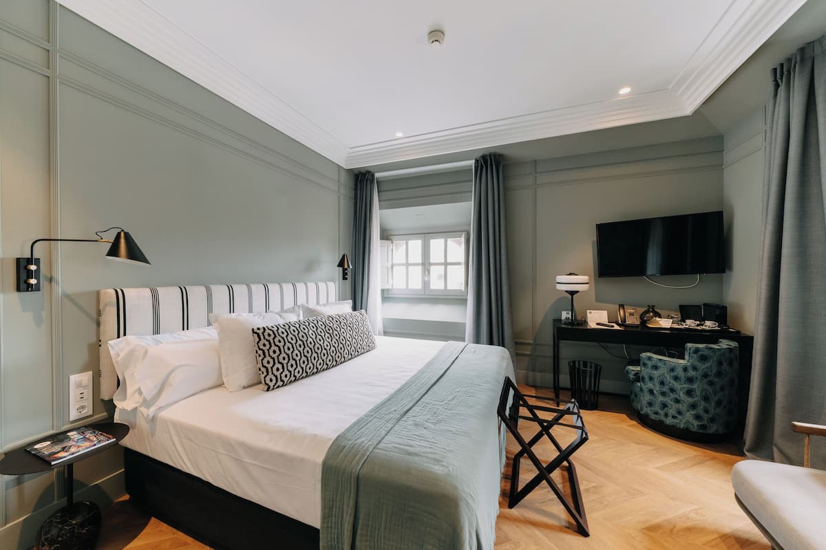 A modern hotel room with a large bed, a desk, and a TV.