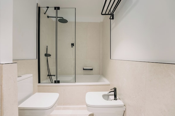 A modern bathroom with a glass-enclosed shower, a white bathtub, and two white toilets. - Petit Palace La Hermosa formerly known as Soho Boutique Colón (Málaga)