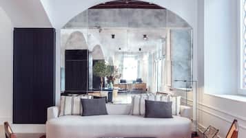 A modern living room with a sofa, two armchairs, a coffee table, and a large arched window.
