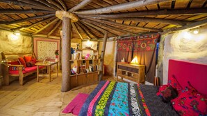 A rustic wooden room with a sloped ceiling, a bed with colorful bedding, a wooden chair, a small table, and a bookshelf. - Le Nid dans les Bruyères (Fere-en-Tardenois)