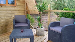 A wooden deck with two wicker chairs and a small table, surrounded by a wooden fence and greenery. - Le Nid dans les Bruyères (Fere-en-Tardenois)