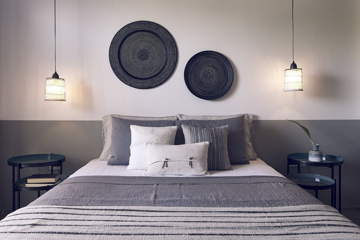 A neatly arranged bedroom with a bed, two wall-mounted round decorative plates, and two hanging pendant lights.