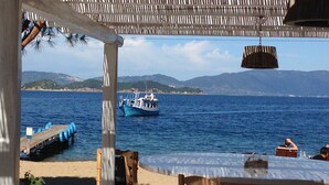 A seaside restaurant with outdoor seating, a wooden deck, and a view of the sea and mountains. - Skiathos Blu (Skiathos)