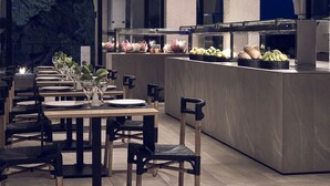 A restaurant with a long counter, black woven chairs, and a glass partition. - Skiathos Blu (Skiathos)