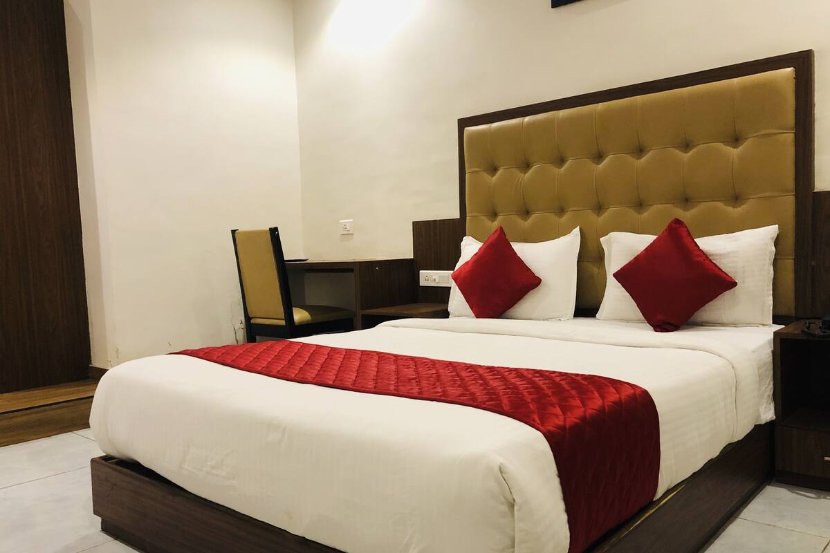 A hotel room with a large bed, a wooden headboard, and a desk with a chair.