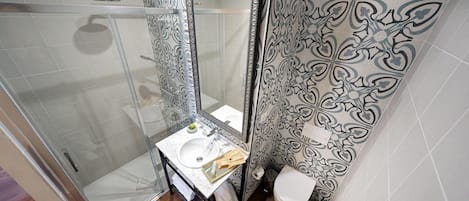 A bathroom with a glass shower enclosure, a sink with a mirror, and a toilet.