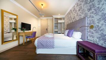 Une chambre d’hôtel comprenant un lit, un bureau avec une chaise, une télévision, un miroir et une armoire.