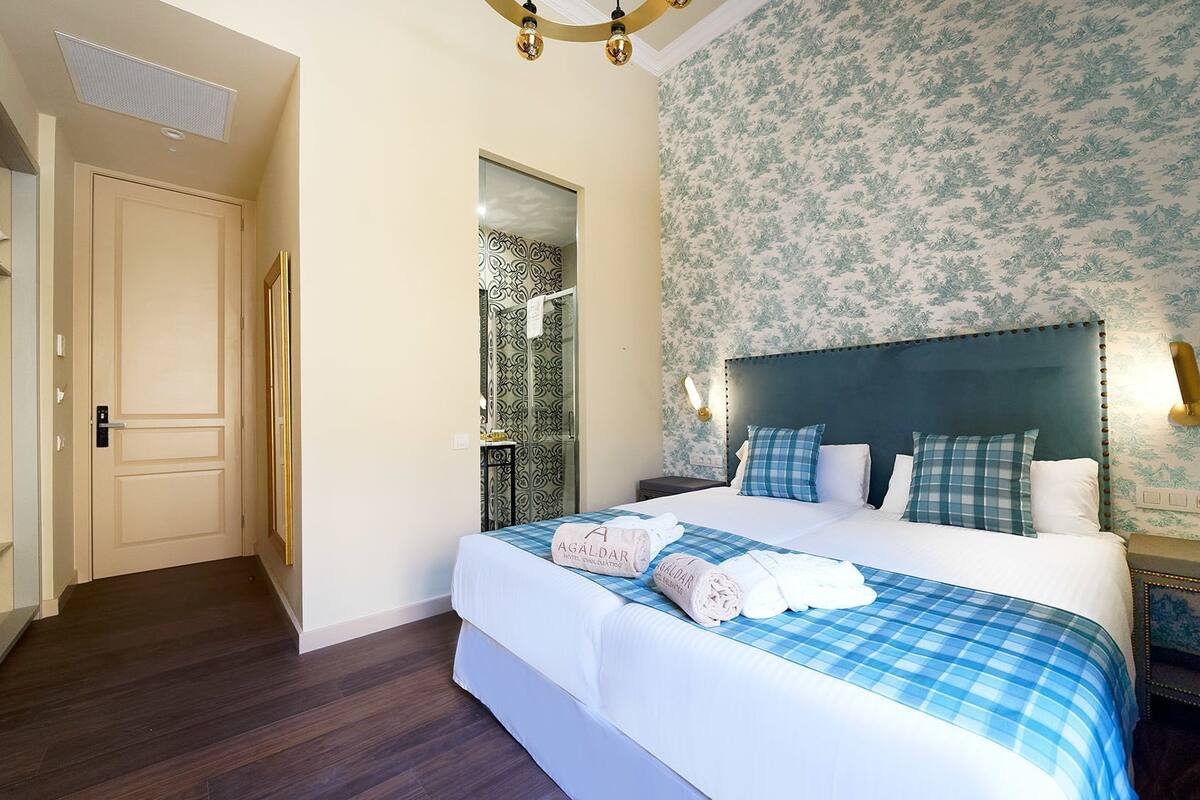 Una habitación de hotel con cama, armario, espejo y ducha.