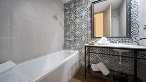 Uma casa de banho com banheira, lavatório e espelho.