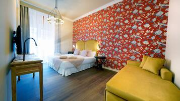 Une chambre d’hôtel avec un lit, une table de chevet, une lampe et un canapé jaune.