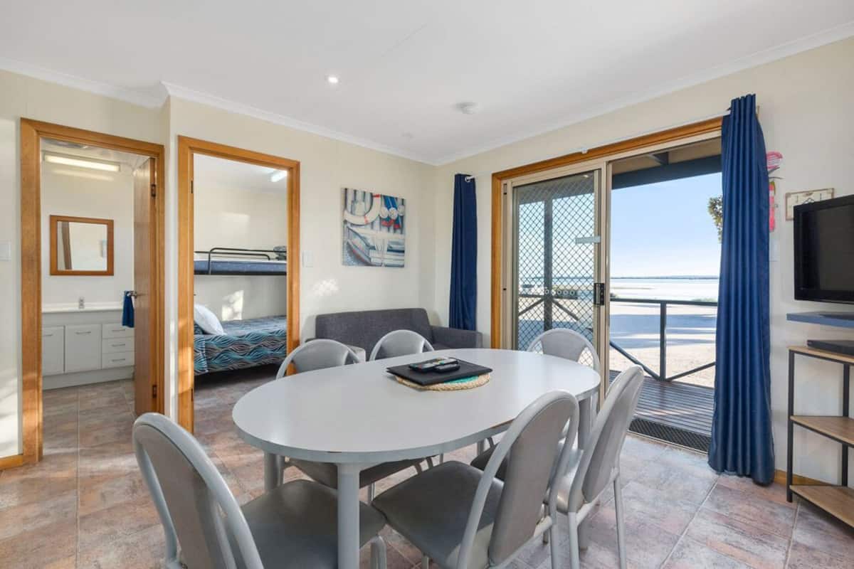Een kamer met een ronde tafel, stoelen, een bed, een televisie en een balkon met uitzicht.