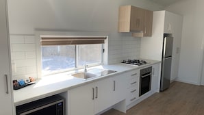 Eine moderne Küche mit weißen Schränken, einem Edelstahl-Kühlschrank, einem Einbauofen und einer Mikrowelle.
