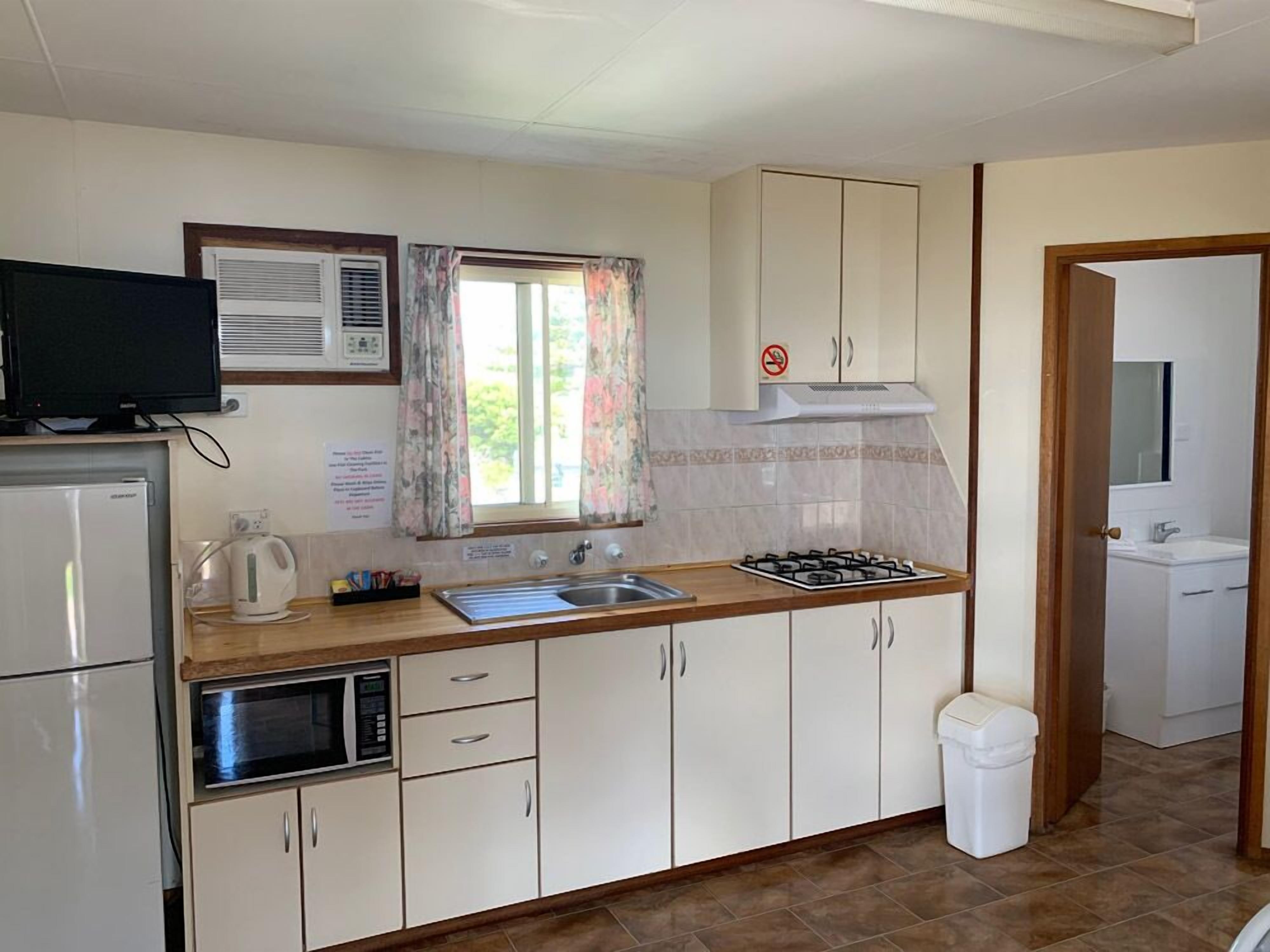 A compact kitchen with a microwave, stove, sink, and cabinets.