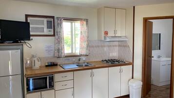A compact kitchen with a microwave, stove, sink, and cabinets.