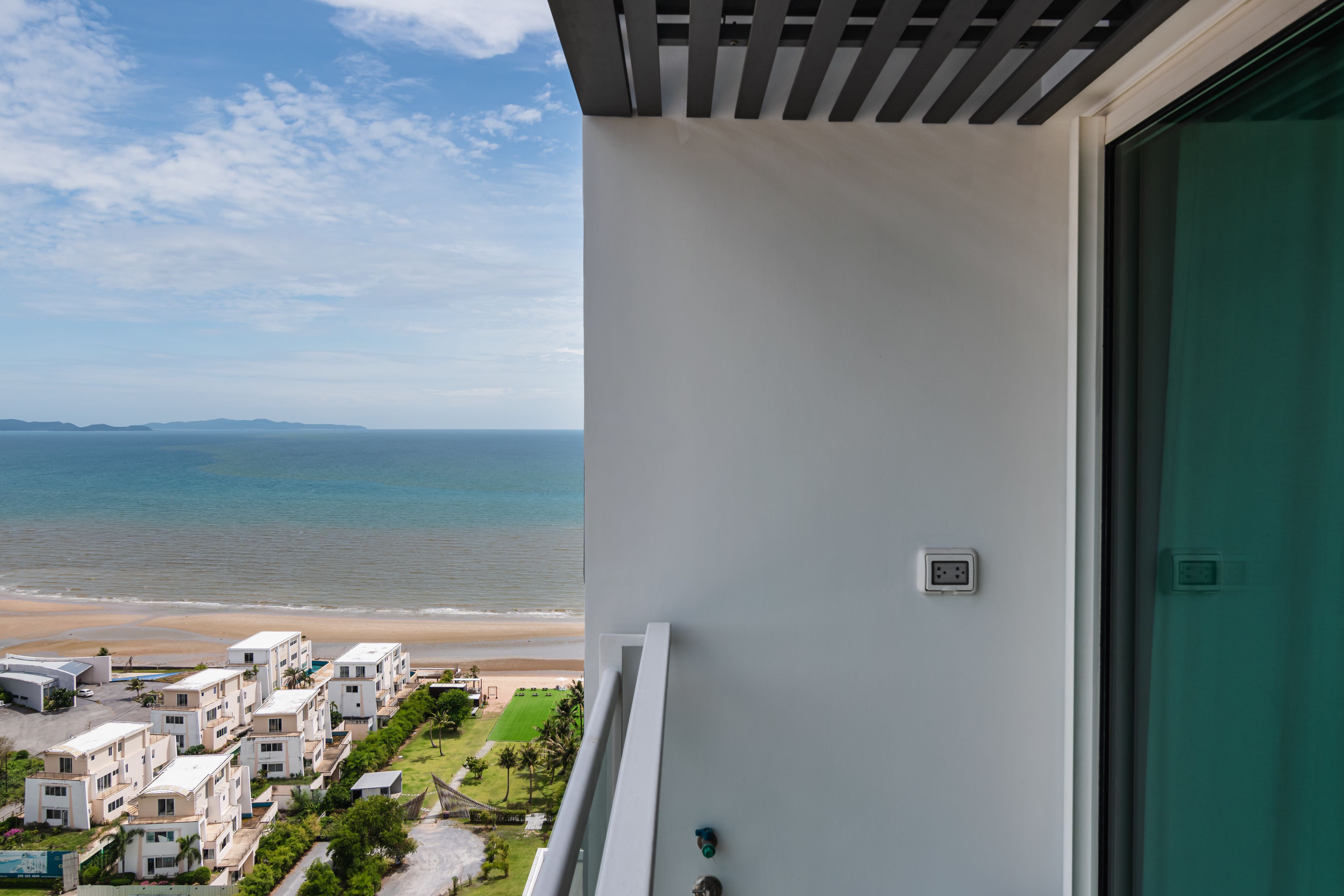 A balcony with a view of the beach and ocean.