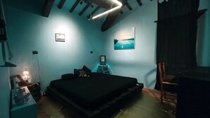 Un dormitorio con cama, escritorio, silla, un cuadro en la pared y ventilador de techo.
