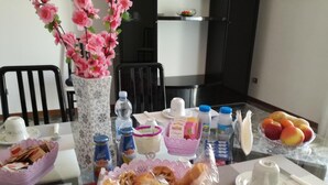 A dining table with food items, beverages, and a vase with flowers. - B&B Luna (Seriate)