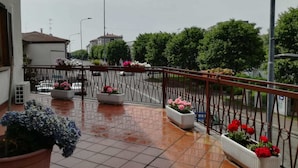 A balcony with tiled flooring, potted plants, and a metal railing. - B&B Luna (Seriate)