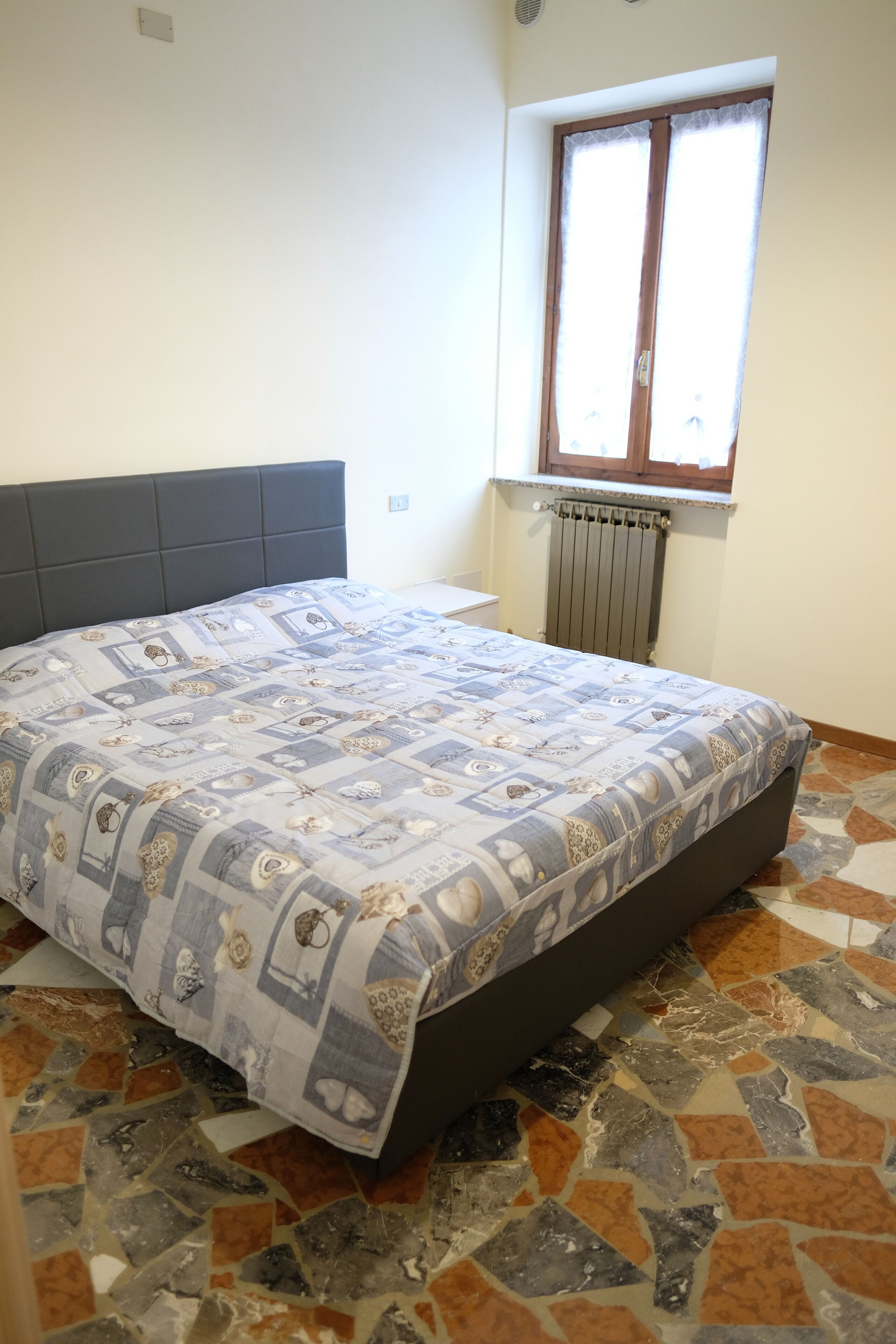 A bedroom with a bed, a window, and a radiator.