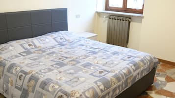 Ein Schlafzimmer mit Bett, Fenster und Heizkörper.