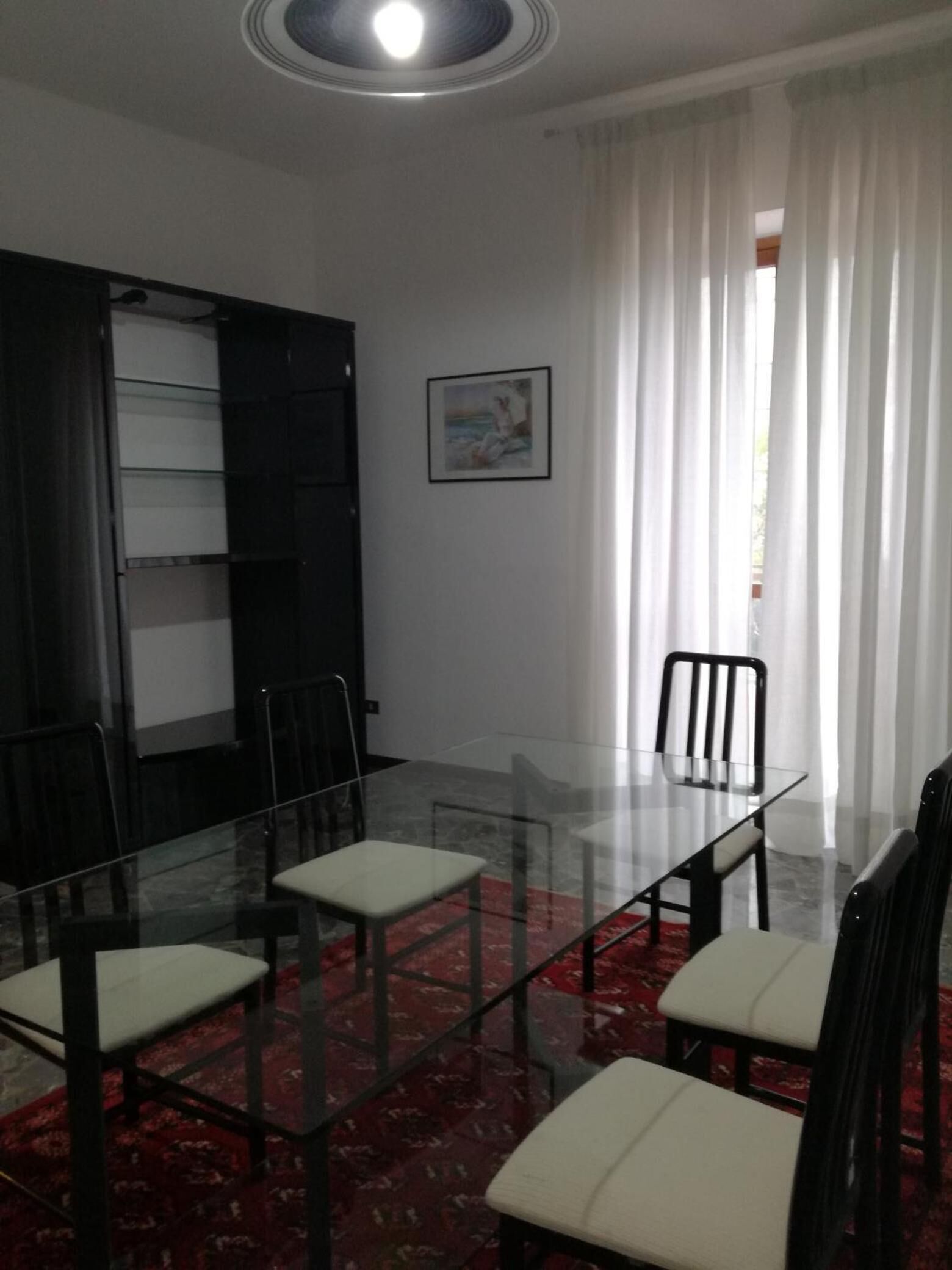 Une salle de conférence avec une table en verre, des chaises noires et un tapis rouge à motifs.