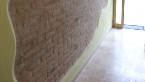 A room with a large brick wall, a yellow wall, and a tiled floor. - B&B Luna (Seriate)