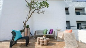 An outdoor seating area with wicker furniture, a wooden table, and a potted plant. - Su Beautiful Homestay (Liuqiu)