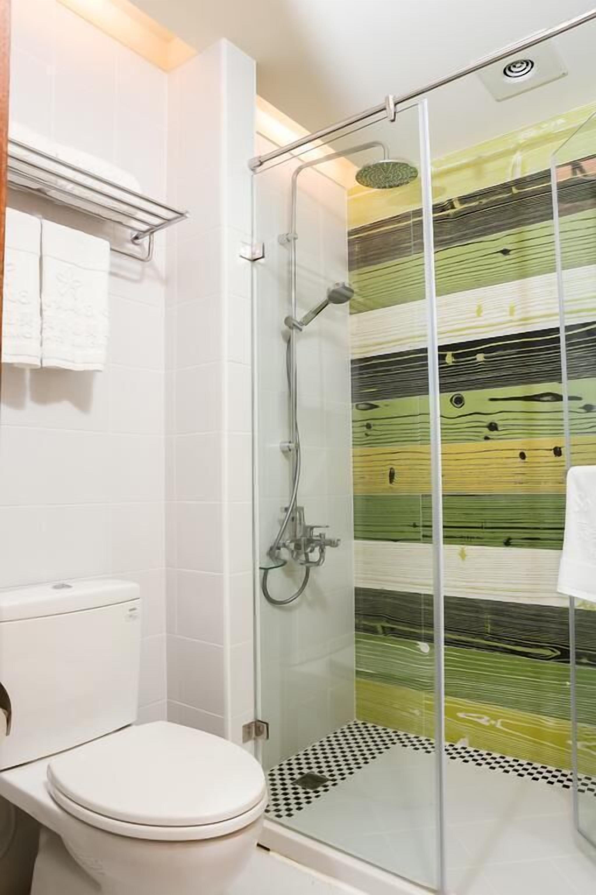 A modern bathroom with a glass-enclosed shower, a white toilet, and a tiled floor.