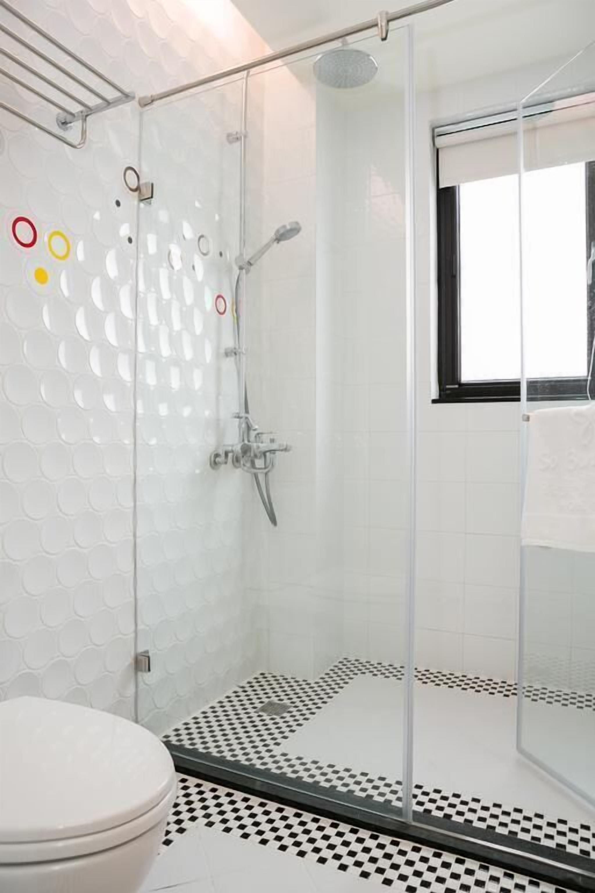 A modern bathroom with a glass shower enclosure, a toilet, and a patterned floor.