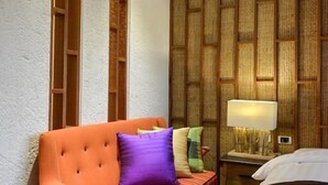 A hotel room with a sofa, a bed, a nightstand with a lamp, and a textured wall panel. - Su Beautiful Homestay (Liuqiu)