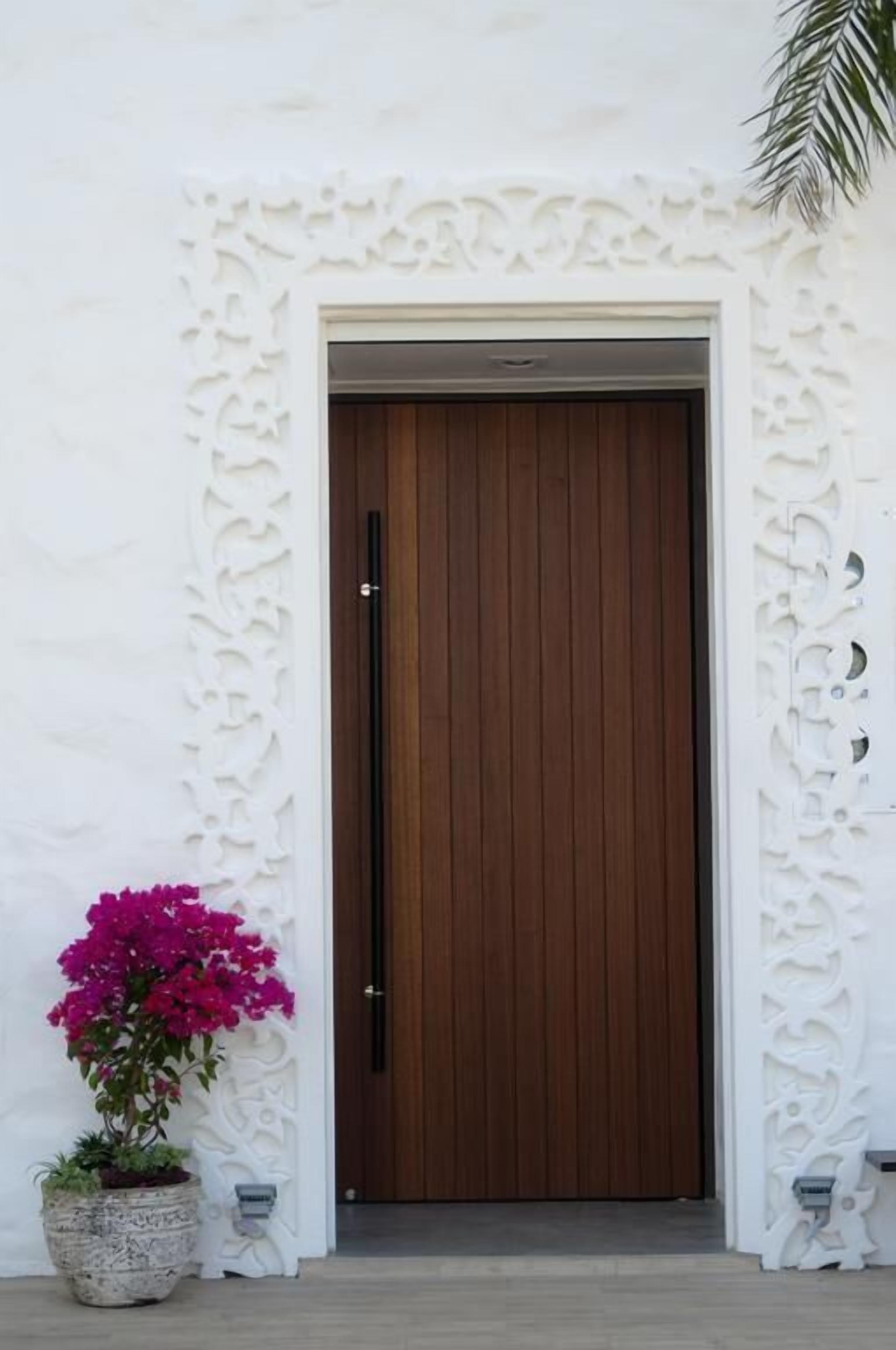 A white wall with a decorative panel and a wooden door.