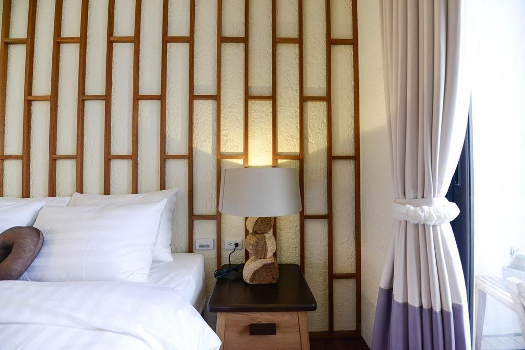 A hotel room with a bed, a nightstand with a lamp, and a curtain.