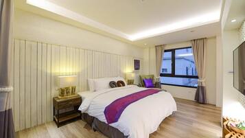 Una habitación de hotel moderna con una cama grande, suelo de madera, una mesita de noche con una lámpara, una ventana con cortinas y un televisor en la pared.
