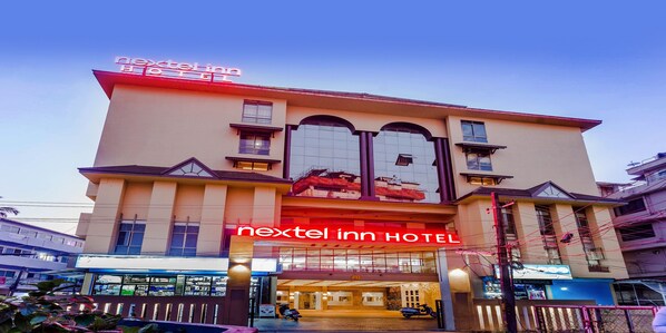 A hotel with a prominent sign reading "nextel inn hotel" and a large glass facade.