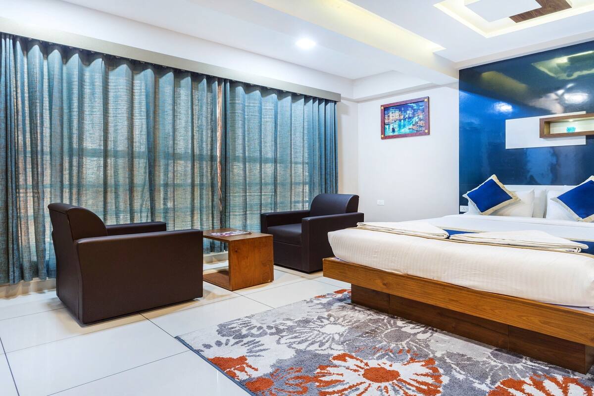 A modern bedroom with a large bed, a sofa, a coffee table, and a TV.