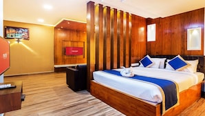 Una habitación de hotel con una cama de madera, televisión de pantalla plana, un escritorio y piso de madera.