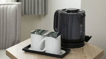 A coffee maker and two white mugs on a tray on a wooden table.