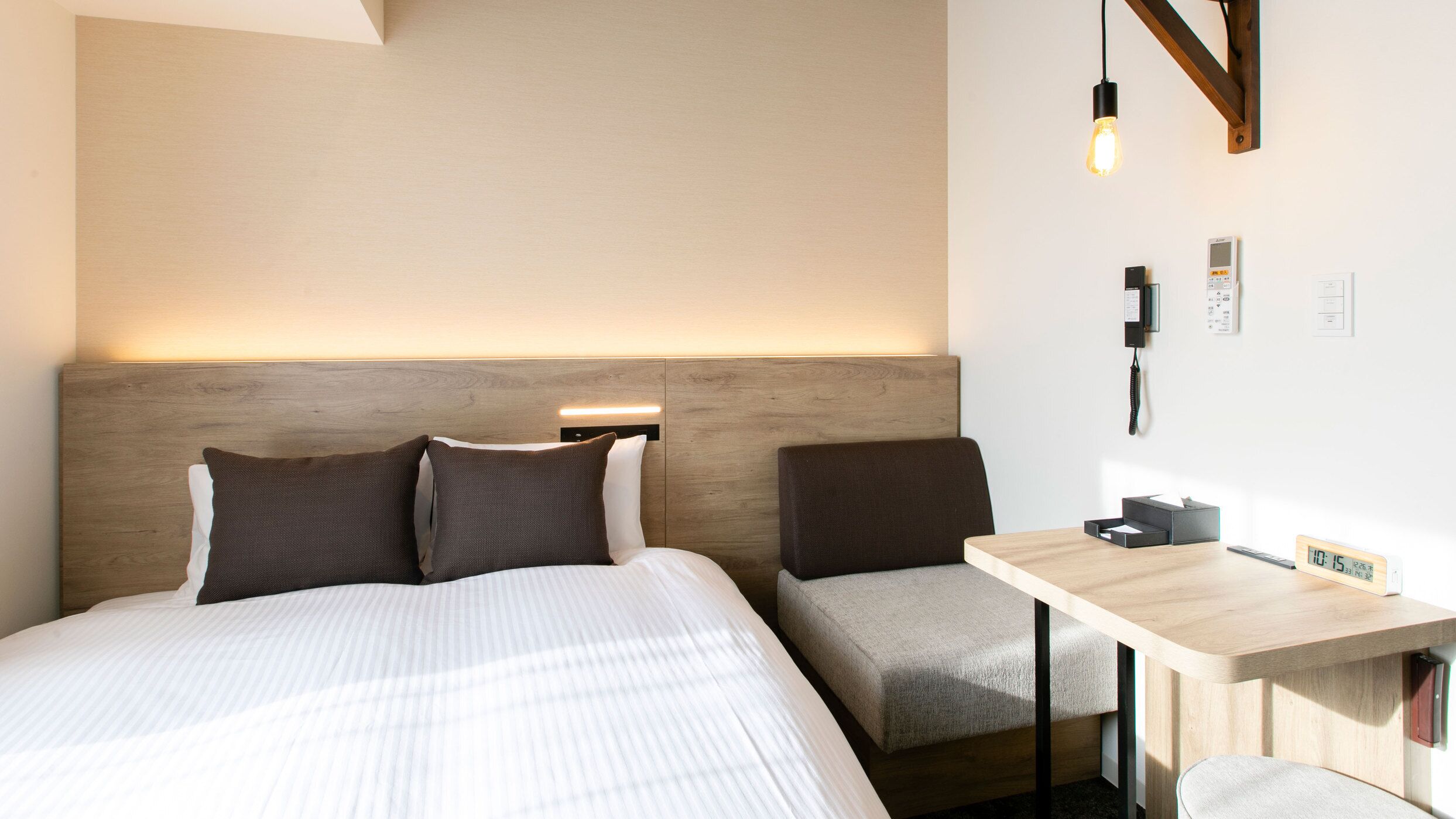 Une chambre d’hôtel équipée d’un lit, de tables de chevet, d’un bureau et d’un téléphone fixé au mur.