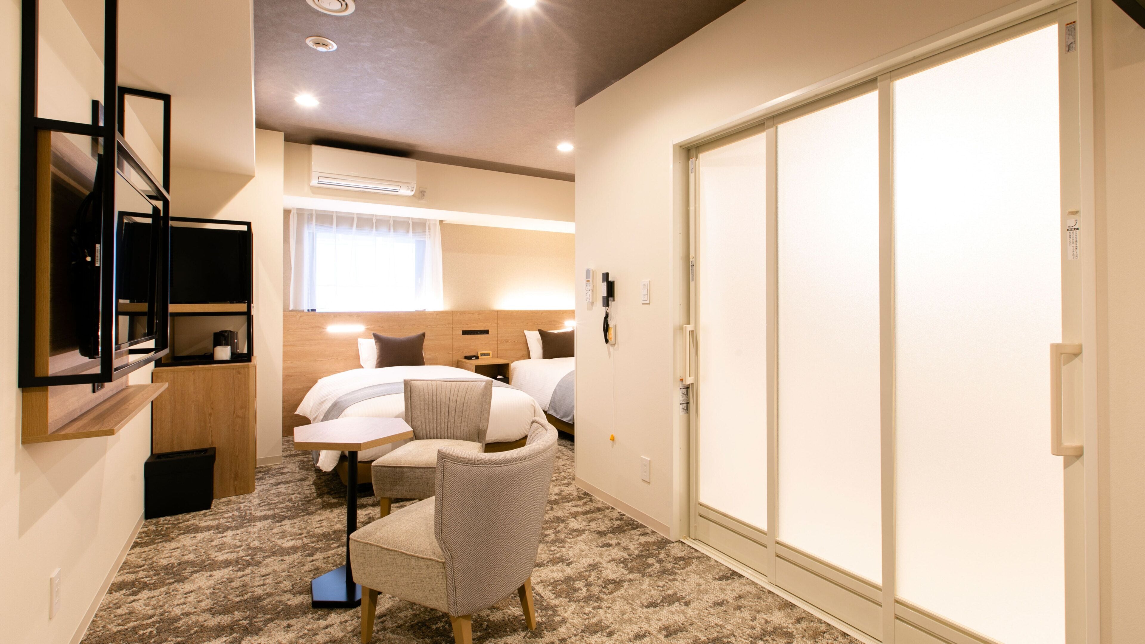 Une chambre d’hôtel comprenant un lit, des tables de chevet, une chaise, un bureau, un téléviseur à écran plat et une armoire.