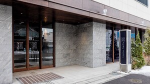 L’extérieur de l’hôtel Koko se caractérise par de grandes portes vitrées, une façade en pierre et une enseigne.