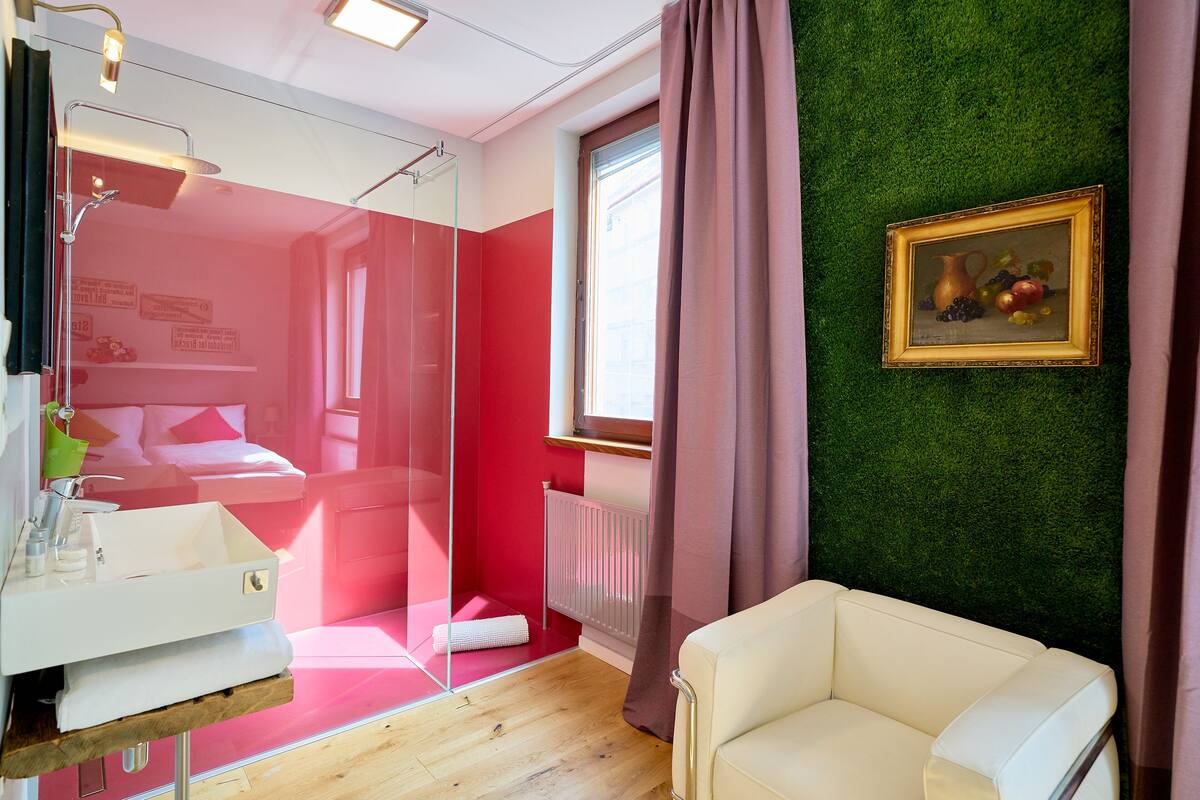 A modern bathroom with a glass shower enclosure, a white sink, and a green wall.