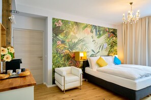 A hotel room with a bed, a chair, a desk with a lamp, and a tropical-themed wall mural. - Leuhusen Center Apartments Vienna (Vienna)