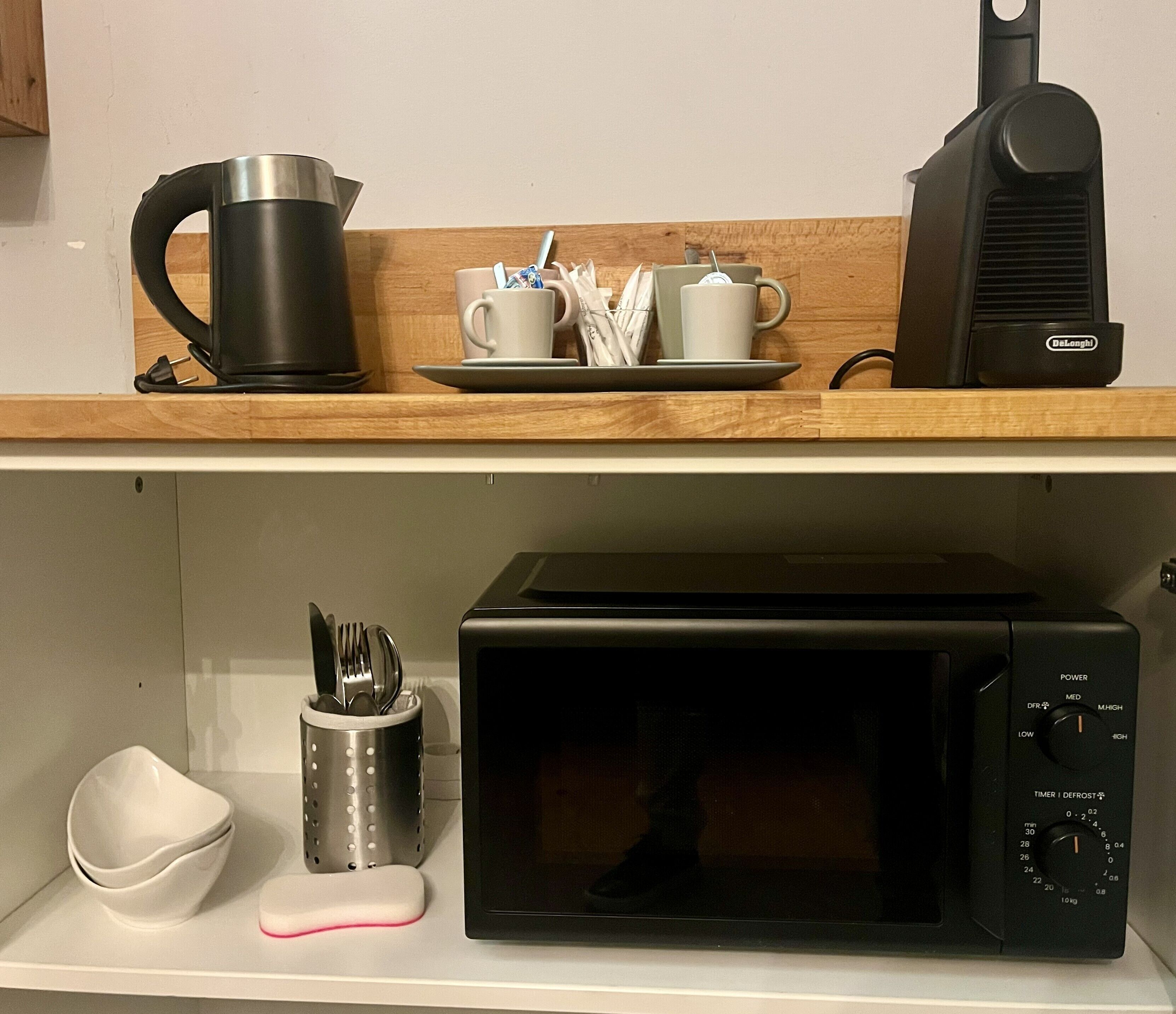 A kitchen area with a microwave, a kettle, and a coffee maker on the countertop.
