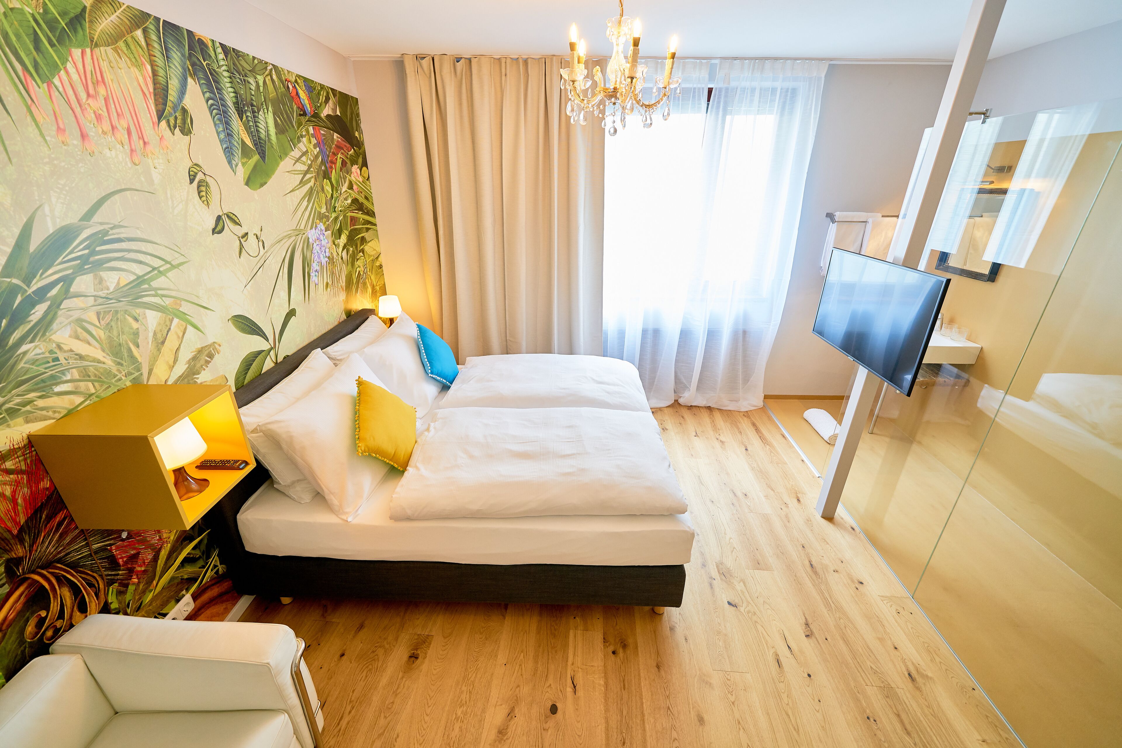 Una habitación de hotel con cama, televisión, candelabro y una pared cubierta de plantas.
