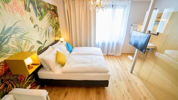 Una habitación de hotel con cama, televisión, candelabro y una pared cubierta de plantas.